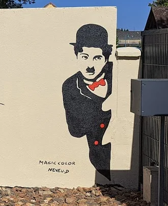 Détail de la fresque : Charlie Chaplin peint en noir avec un nœud rouge, et la signature MAGIC COLOR NEVEU.D.