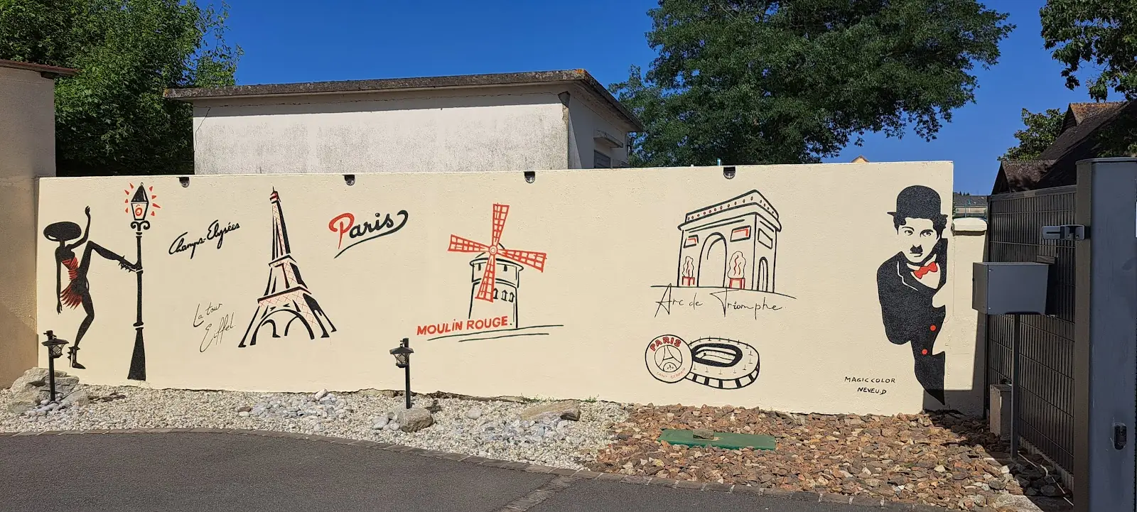 Fresque peinte par Magic Color sur un mur extérieur : danseuse, tour Eiffel, Moulin Rouge, Arc de Triomphe et Charlie Chaplin, en noir et rouge sur fond crème.